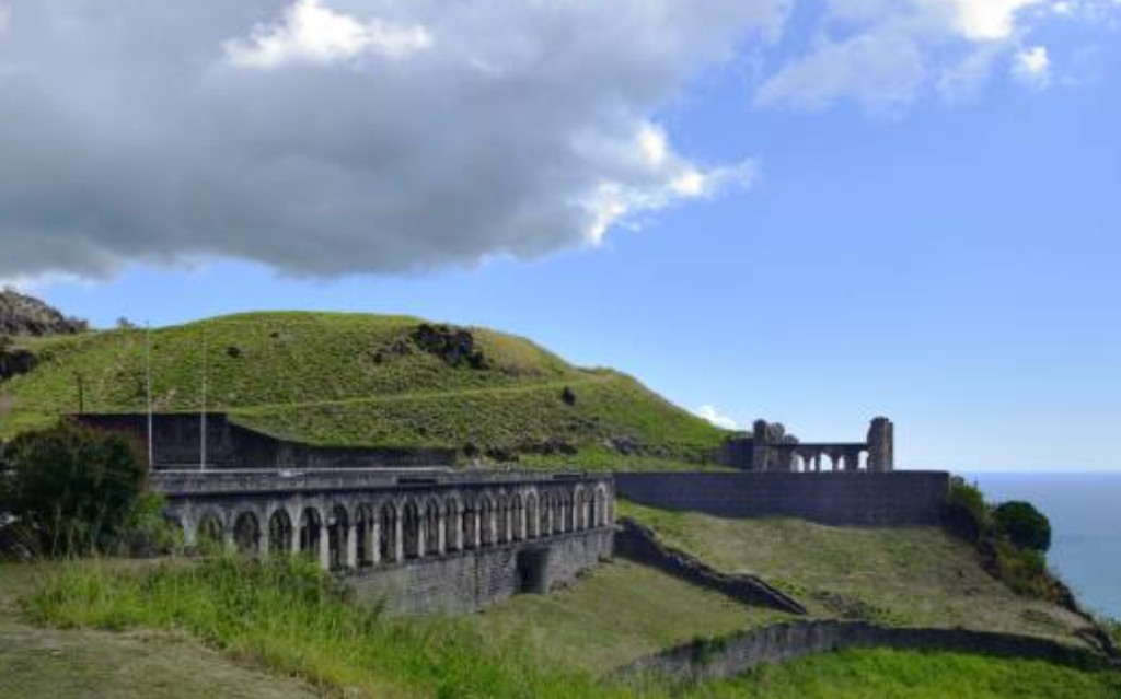 Brimstone Hill Fortress arched stone galleries on a grassy hillside overlooking the Caribbean