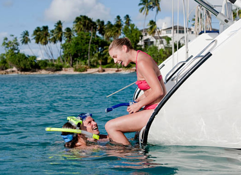 Snorkellers boarding a St Kitts catamaran from turquoise Caribbean water
